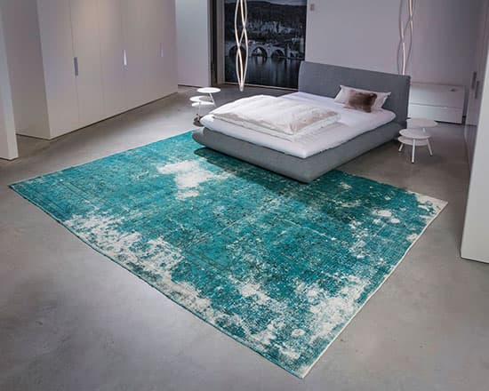 türkis farbener decolorized teppich in einem Schlafzimmer unter einem weißem doppelbett