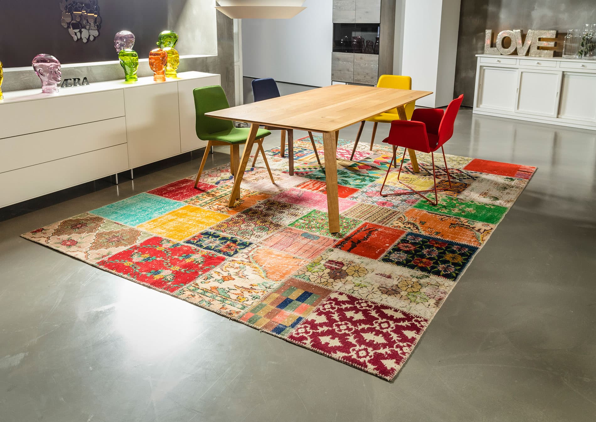 exclusiver designer teppich mit einem buntem patchwork muster in einer mordernen küche mit sideboard, einem holztisch und stühlen