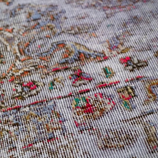 Nahaufnahme eines Persian Art Design Teppich mit farbigem Muster auf hell lila farbenem Webgeflecht