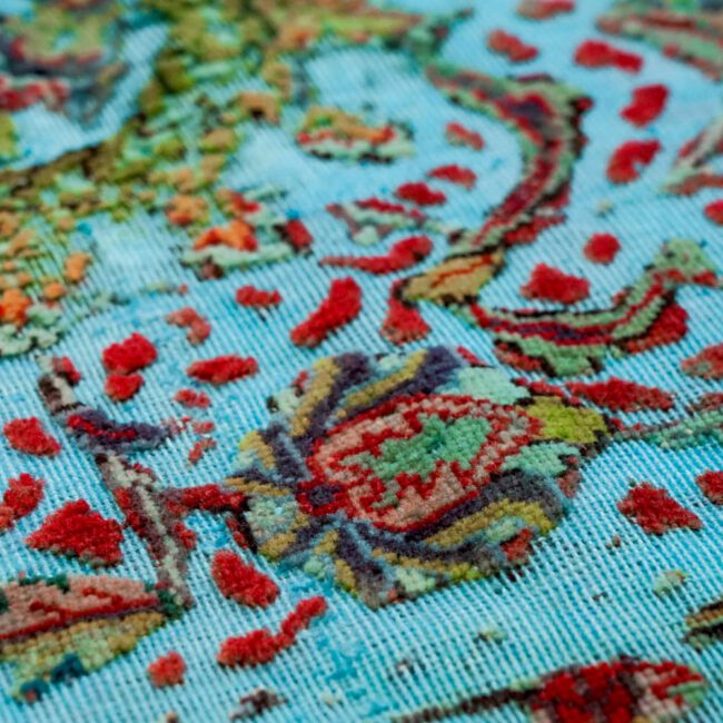Nahaufnahme eines Persian Art Design Teppich mit farbigem Muster auf hell türkisblau farbenem Webgeflecht