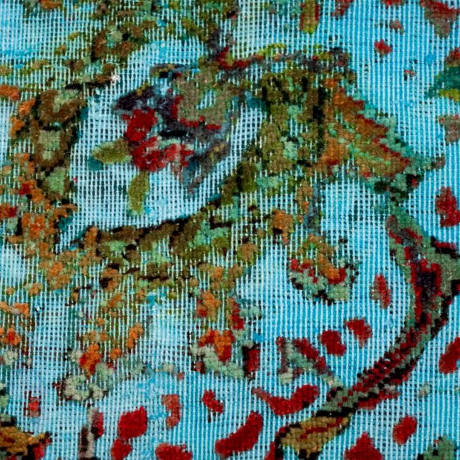 Nahaufnahme eines Persian Art Design Teppich mit farbigem Muster auf hell türkisblau farbenem Webgeflecht