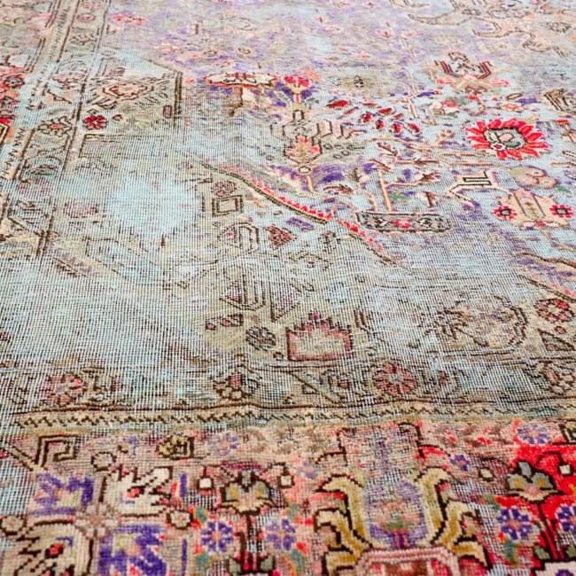 Close Up von einem Persian Art Design Teppich mit dunkel farbigem Muster auf grün bläulich farbenem Webgeflecht