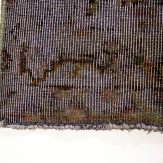 Close Up von einem Persian Art Design Teppich mit dunkel farbigem Muster auf grau aubergine farbenem Webgeflecht